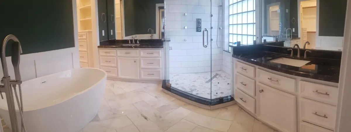 Completed MSS bathroom remodel with a freestanding tub, corner glass shower, and dual granite-topped vanities